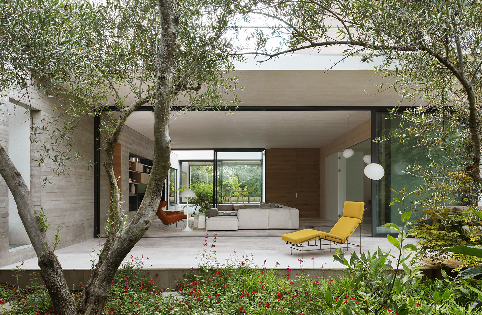 Vista desde el jardín del porche con acceso al salón de la Casa CH construida en madera